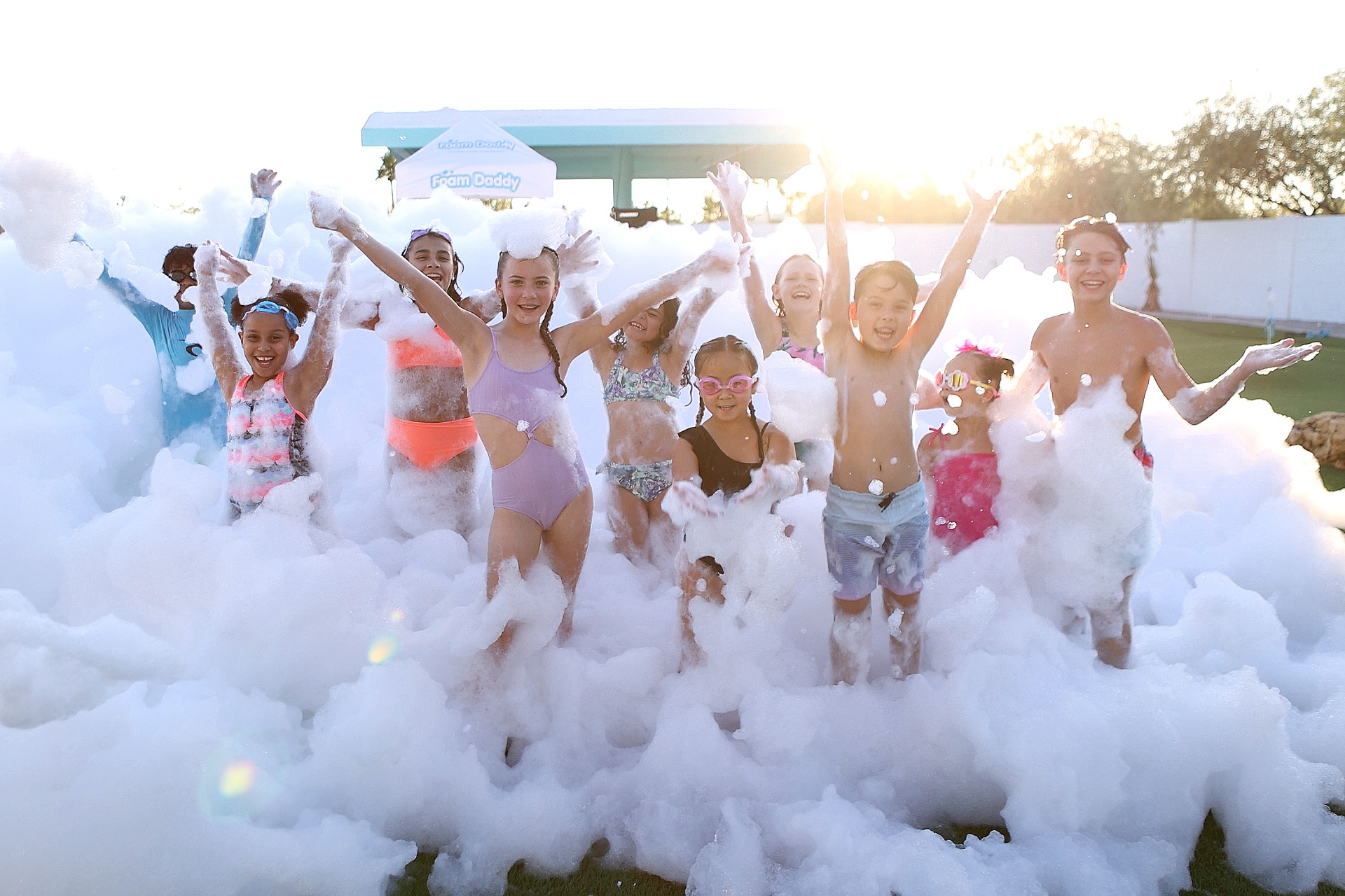 Kids cheering in a mountain of foam at an outdoor foam party