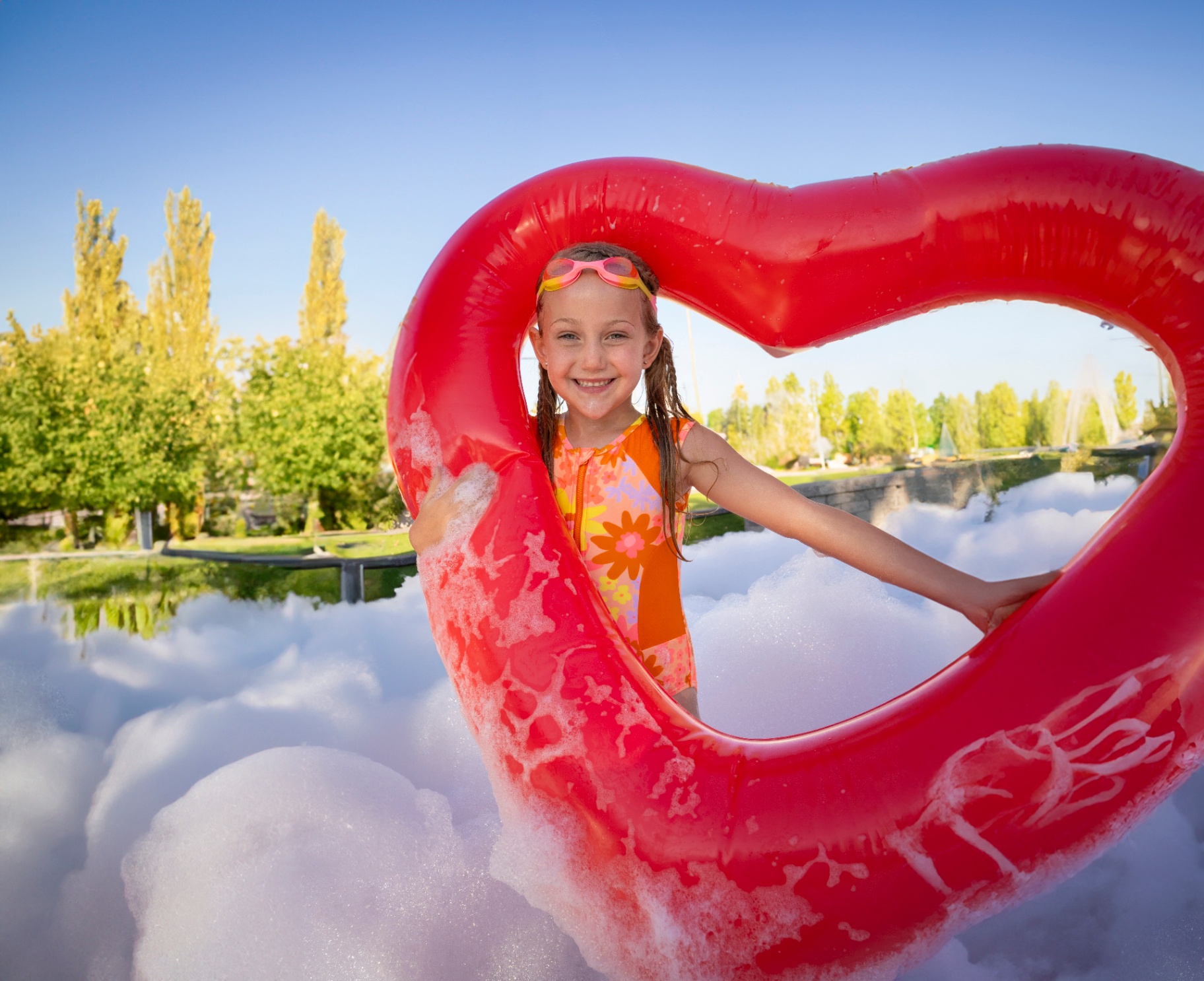 Smiling girl framed by a red heart float in foam